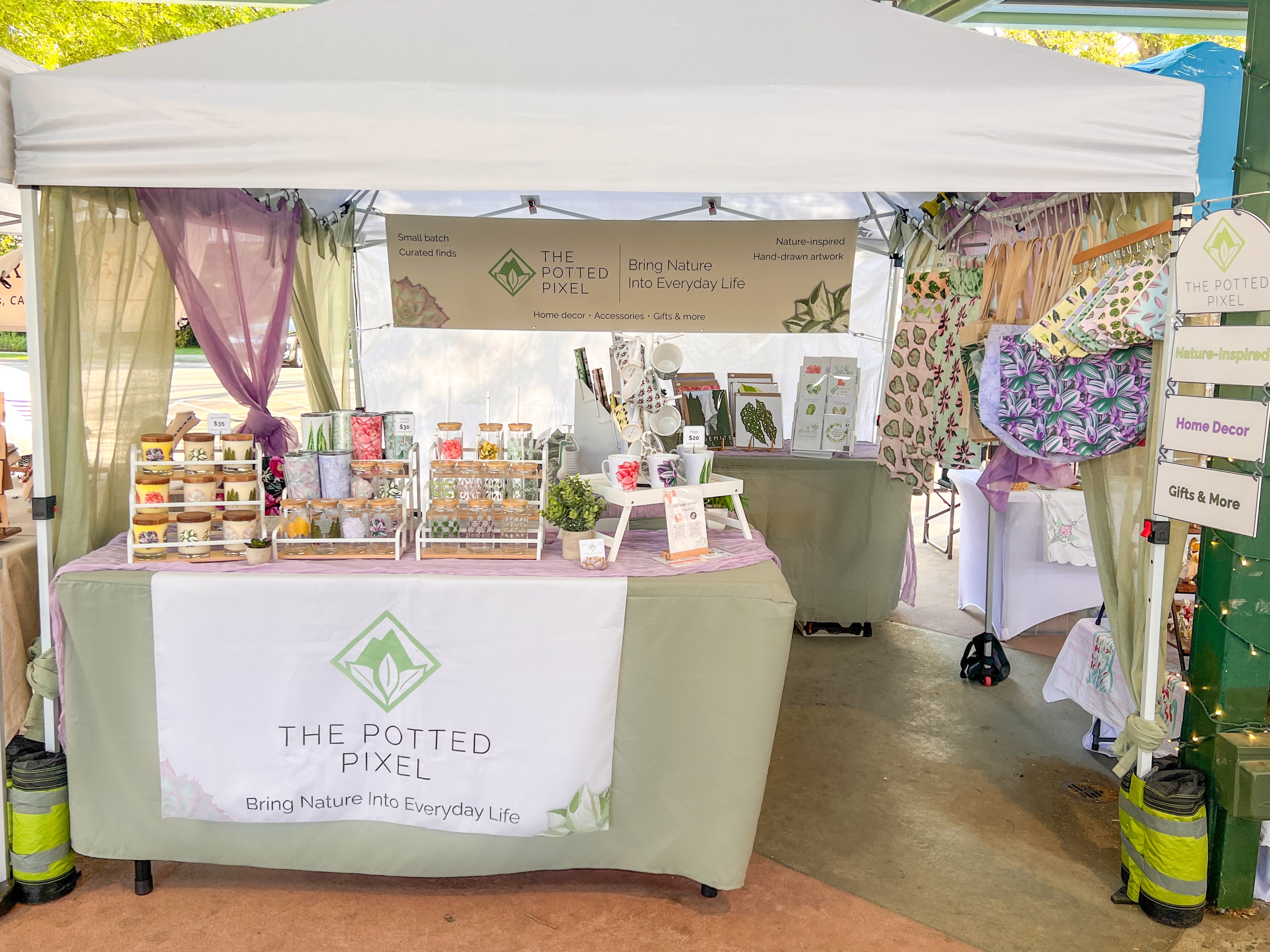 Outdoor event with a booth labeled 'The Potted Pixel' displaying various items.